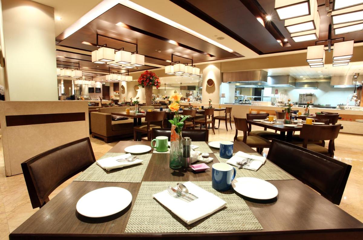 a dining room with tables and chairs in a restaurant at The LaLiT New Delhi in New Delhi