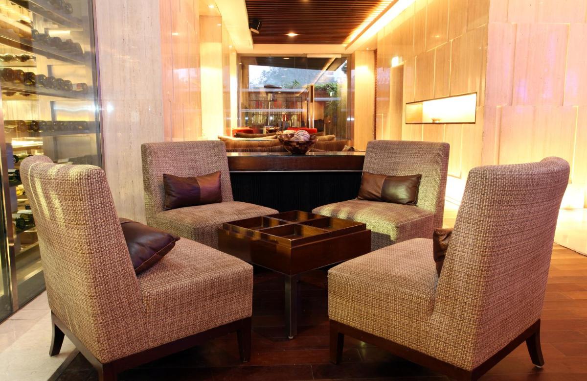 a lobby with chairs and a table and a bar at The LaLiT New Delhi in New Delhi