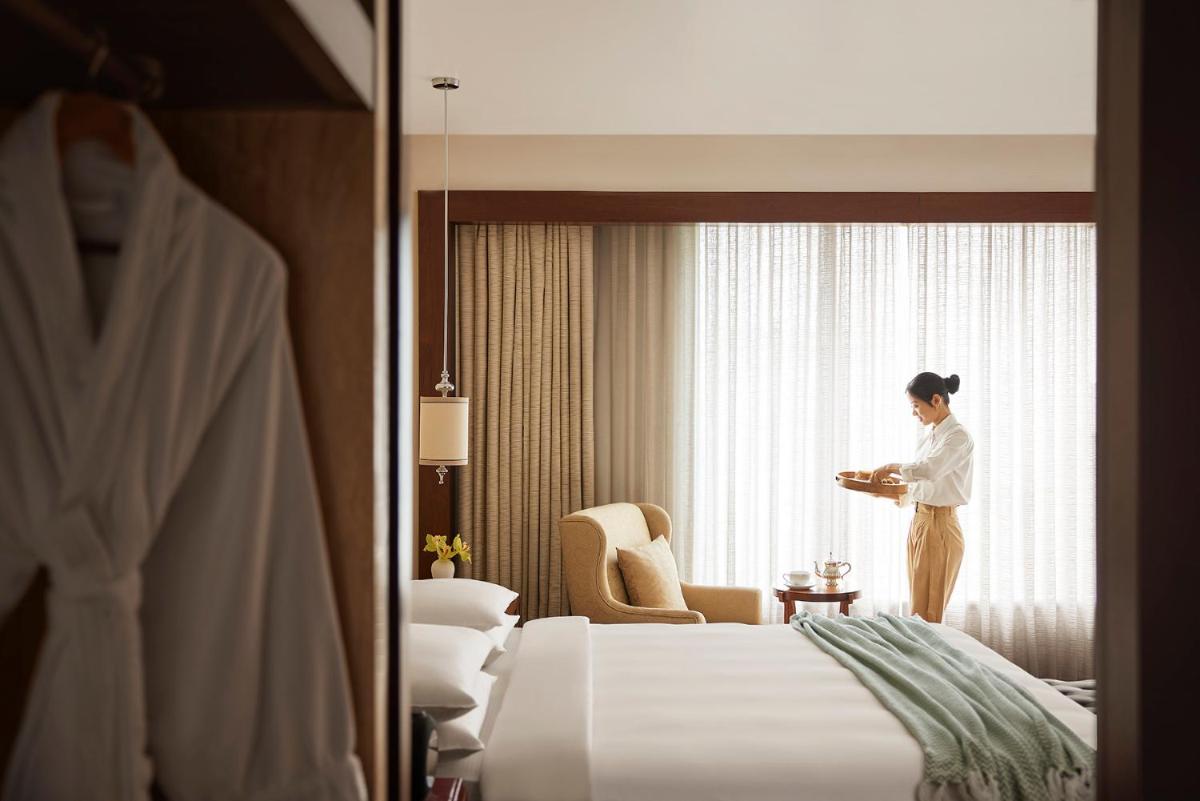 a woman standing in a hotel room looking out the window at Park Hyatt Chennai in Chennai