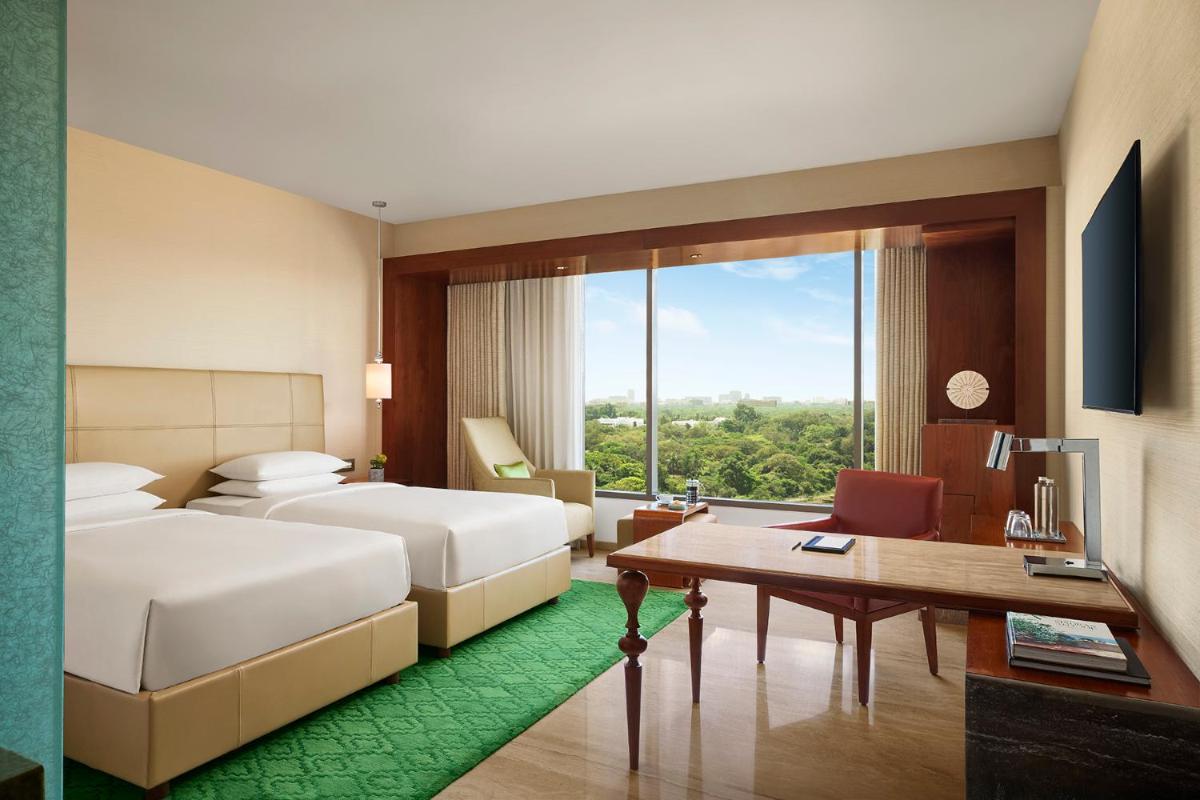 a hotel room with two beds and a desk at Park Hyatt Chennai in Chennai
