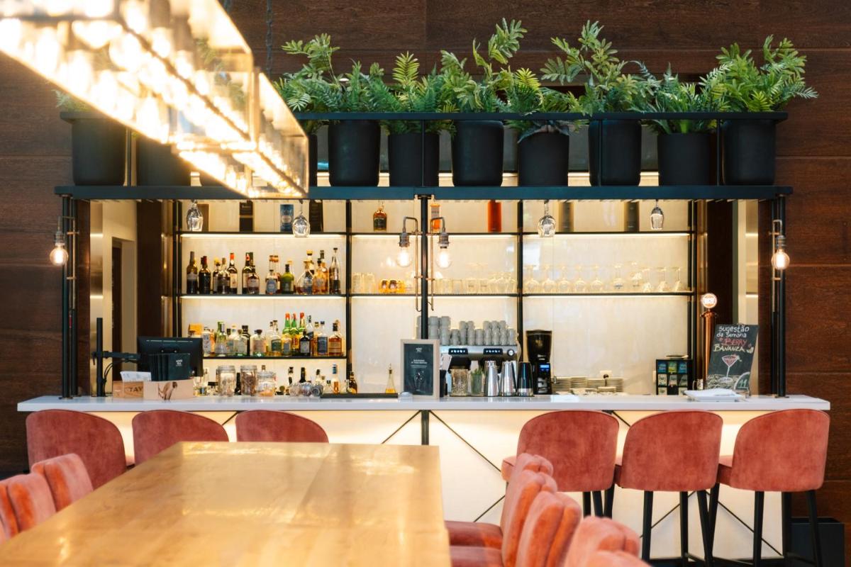 um bar com mesas, cadeiras e plantas em vasos em Monte Real - Hotel, Termas & Spa em Monte Real