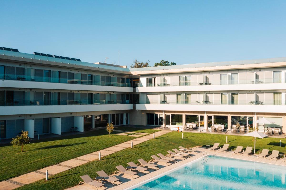 uma vista exterior de um hotel com uma piscina e cadeiras em Monte Real - Hotel, Termas & Spa em Monte Real