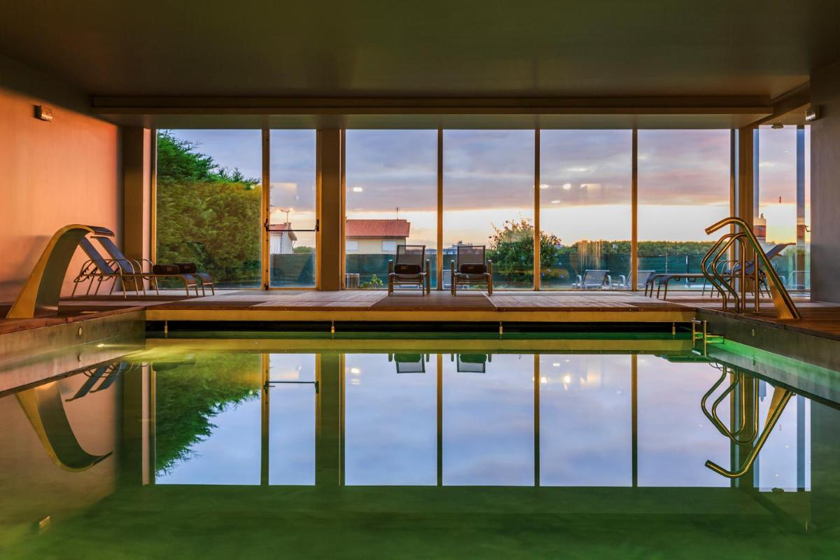 uma piscina com cadeiras e vista para a água em Villa C Boutique Hotel em Vila do Conde