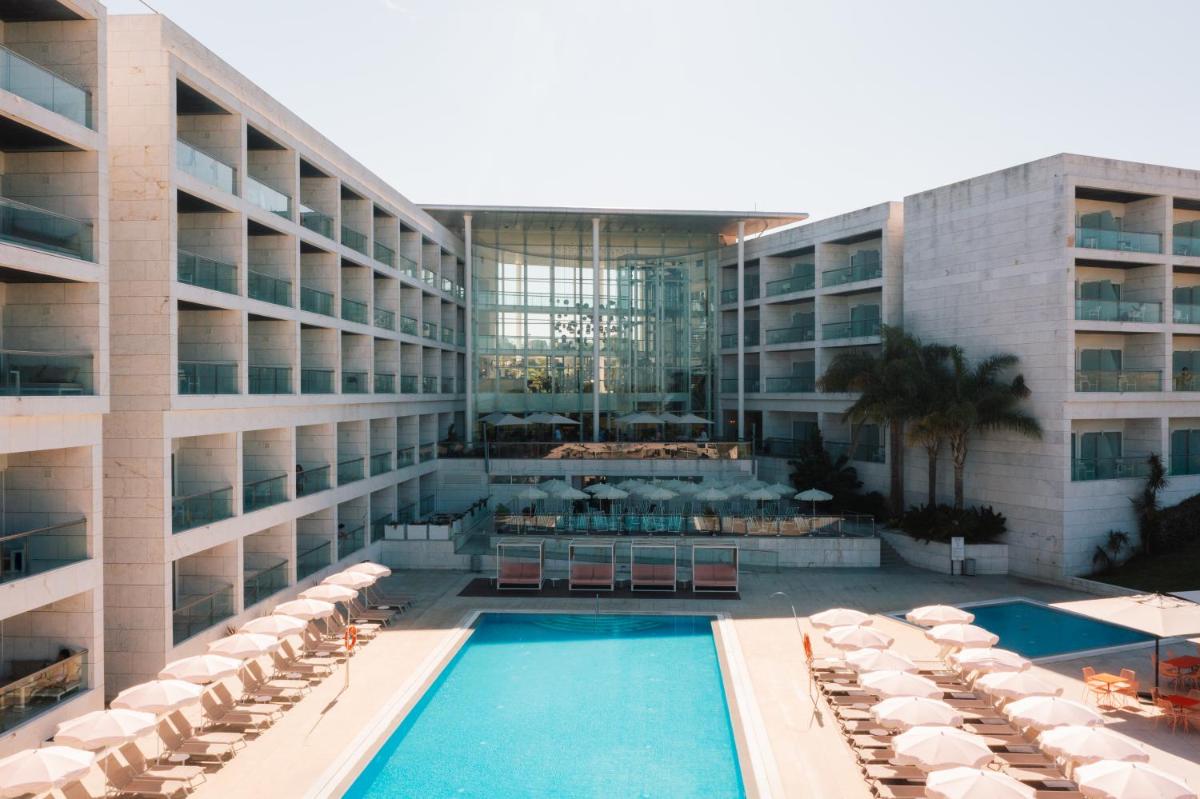 um hotel com piscina em frente a um prédio em Crowne Plaza - Caparica Lisbon em Costa da Caparica