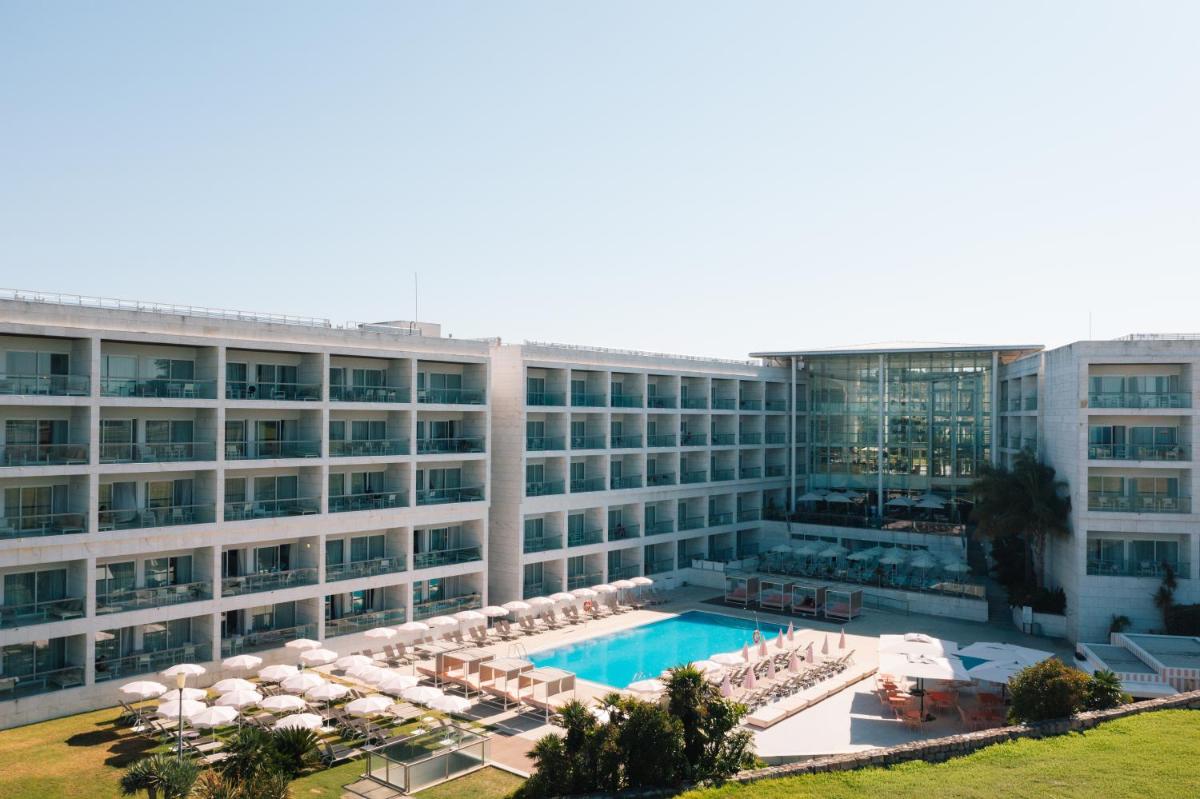 um grande edifício com piscina e guarda-sóis em Crowne Plaza - Caparica Lisbon em Costa da Caparica