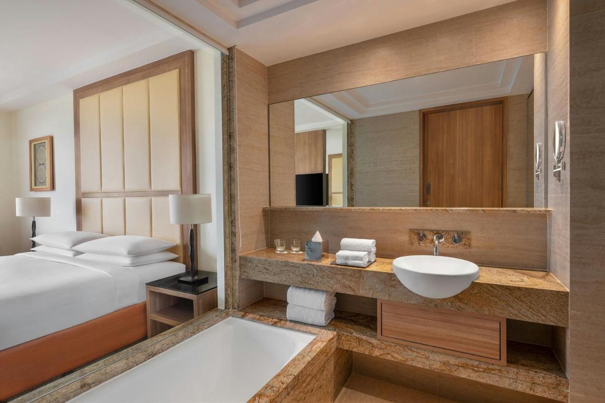 a bathroom with a bed and a sink and a mirror at Bengaluru Marriott Hotel Whitefield in Bengaluru