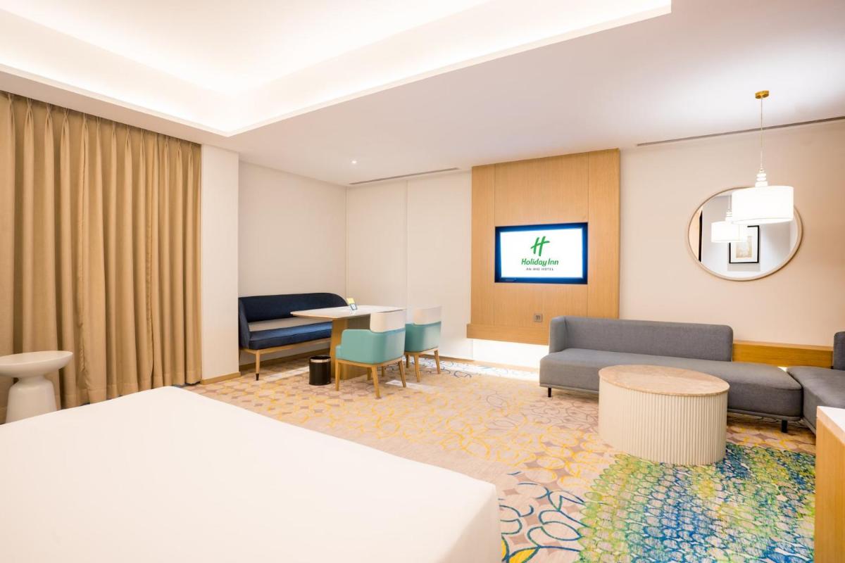 a hotel room with a bed and a couch and a table at Holiday Inn Lucknow Airport by IHG in Lucknow