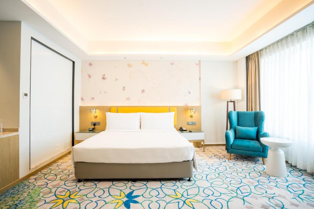 a bedroom with a bed and a blue chair at Holiday Inn Lucknow Airport by IHG in Lucknow