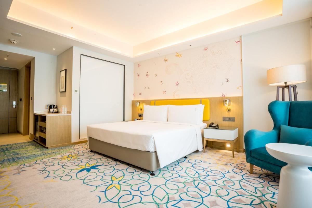 a hotel room with a bed and a blue chair at Holiday Inn Lucknow Airport by IHG in Lucknow
