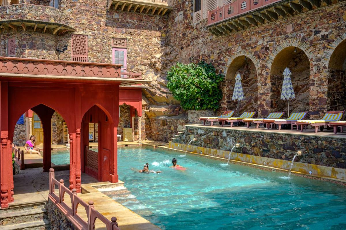 a pool in a building with two people in the water at Neemrana Fort-Palace in Neemrana