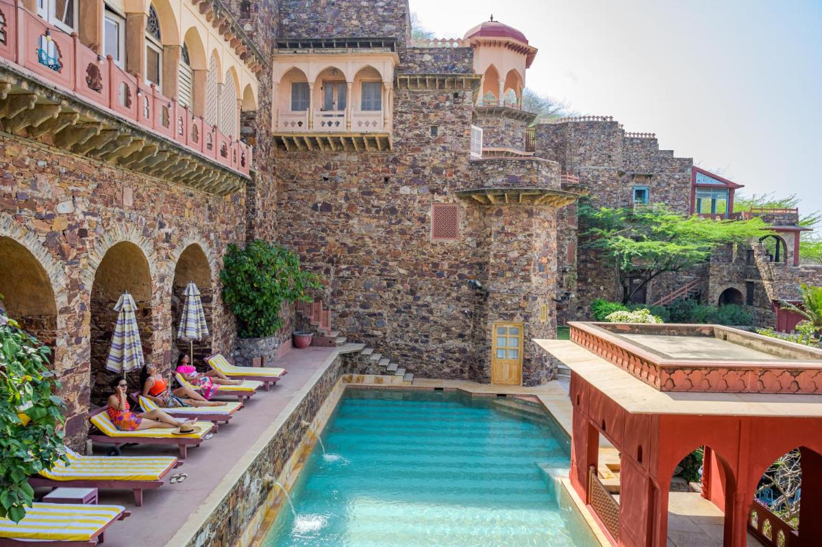 a pool in a building with people sitting on chairs next to it at Neemrana Fort-Palace in Neemrana