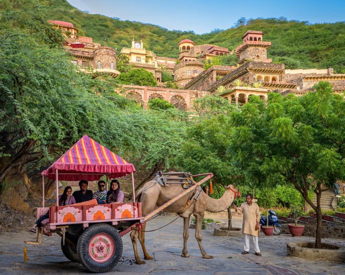 a group of people riding in a cart pulled by a camel at Neemrana Fort-Palace in Neemrana