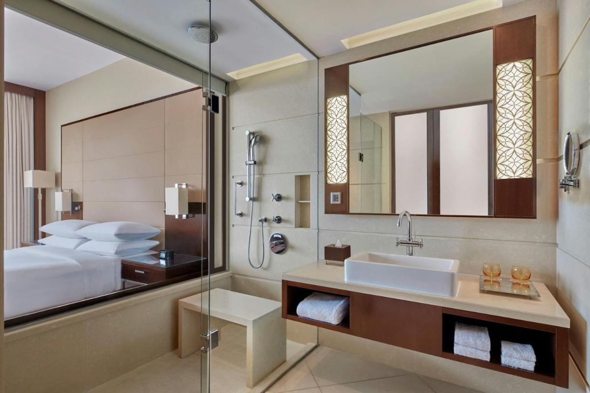 a bathroom with a bed and a sink and a mirror at Kochi Marriott Hotel in Cochin