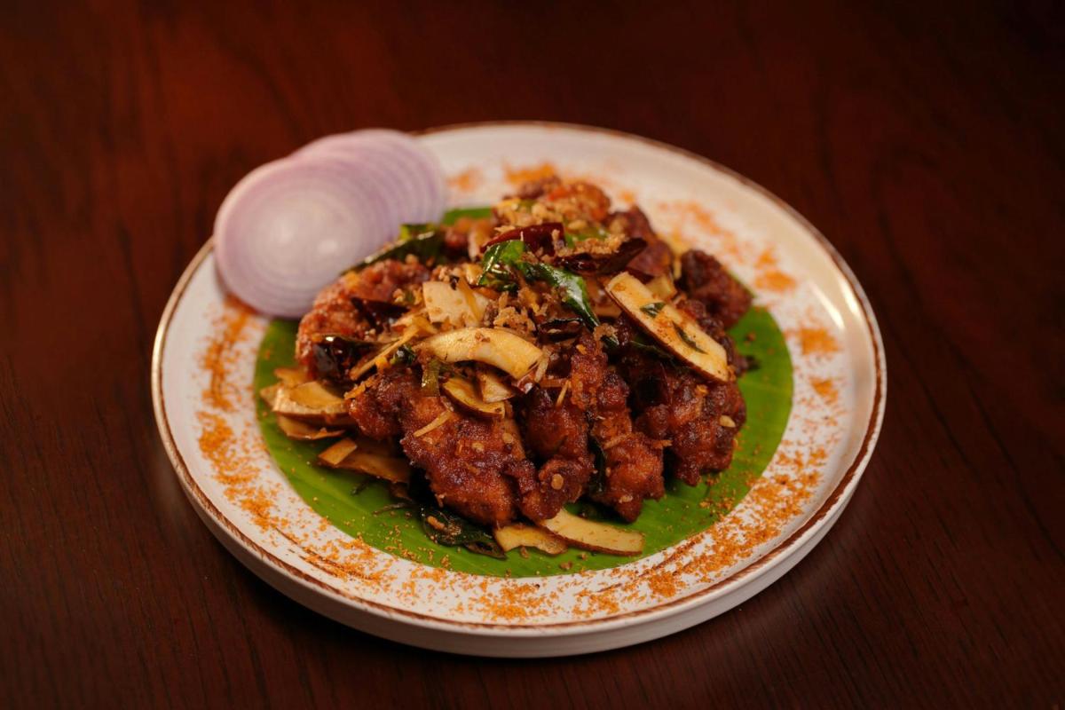 a plate of food with meat and onions on a table at Kochi Marriott Hotel in Cochin