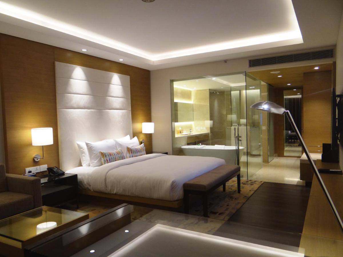 a bedroom with a bed and a bathroom with a tub at Feathers- A Radha Hotel, Chennai in Chennai
