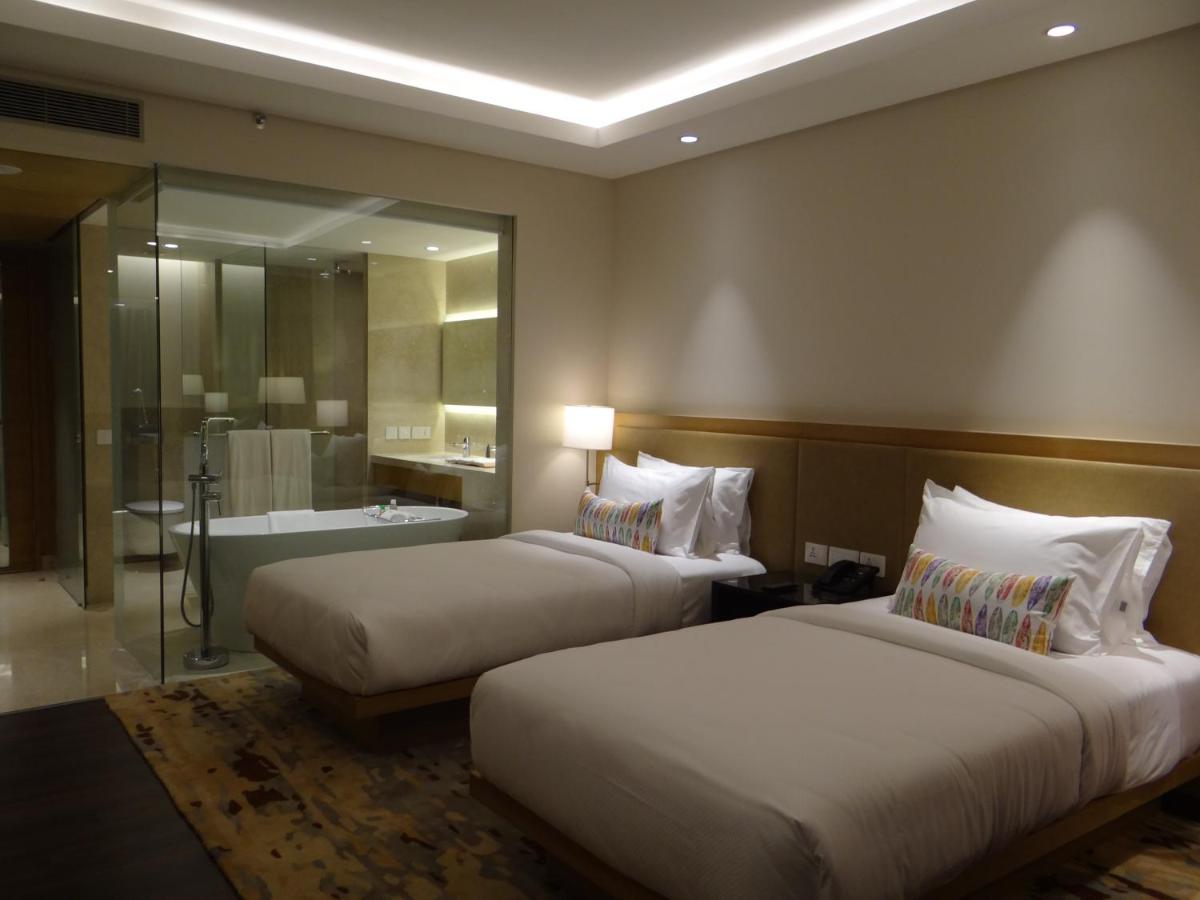 two beds in a hotel room with a bathroom at Feathers- A Radha Hotel, Chennai in Chennai