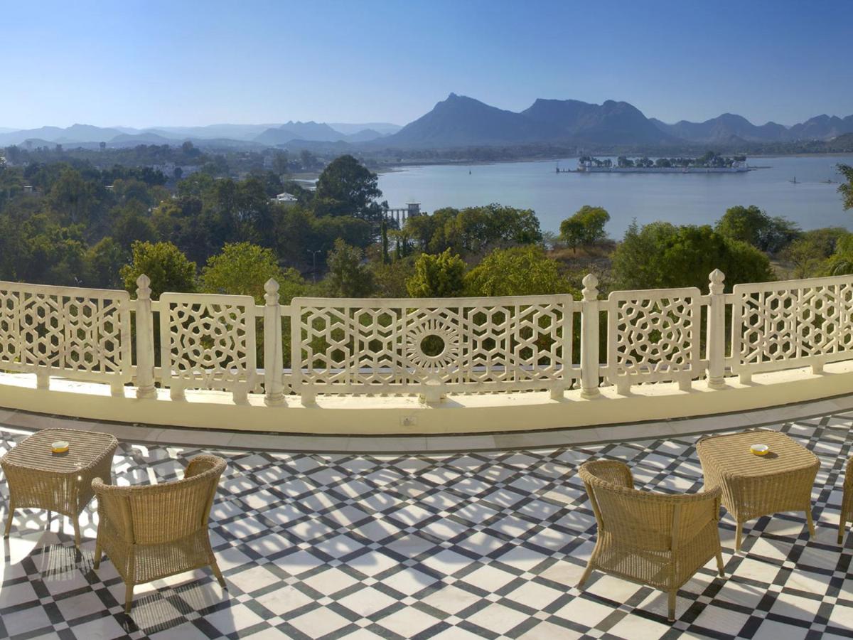 a white fence on a patio with tables and chairs at The Lalit Laxmi Vilas Palace in Udaipur
