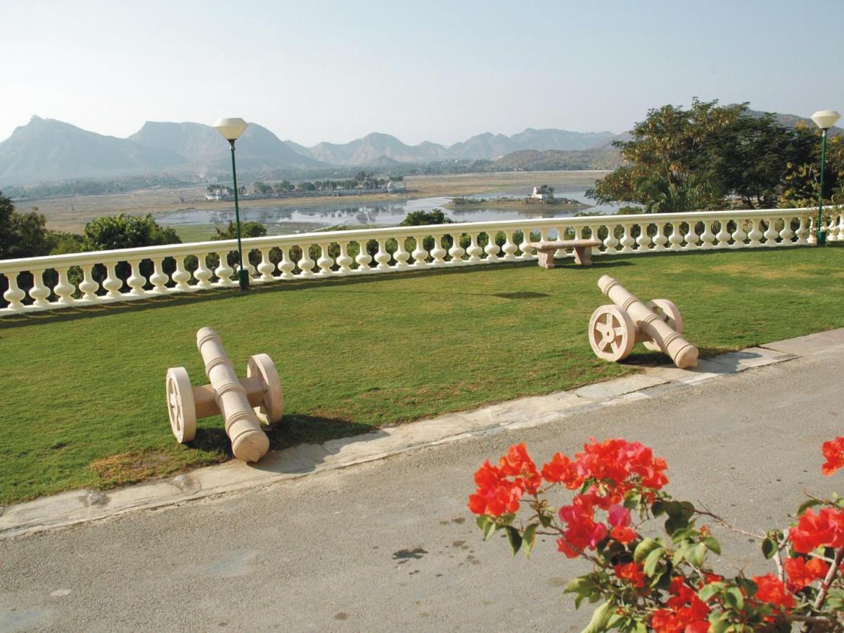 a row of benches on the side of a road with flowers at The Lalit Laxmi Vilas Palace in Udaipur