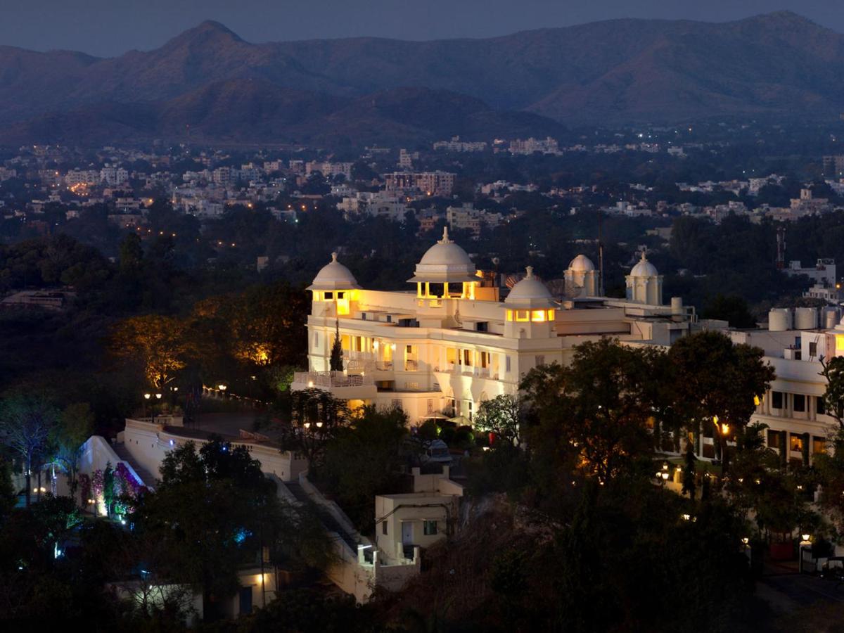 a large white building with a city at night at The Lalit Laxmi Vilas Palace in Udaipur