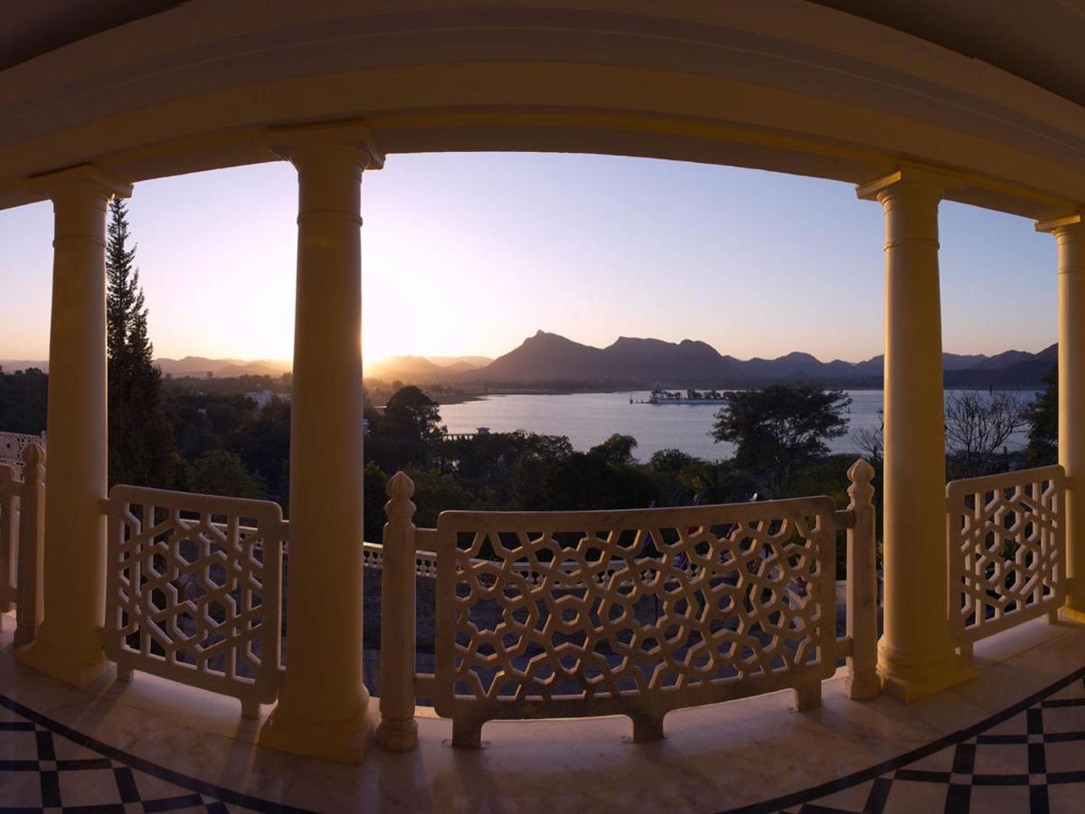 a porch with a view of the water and mountains at The Lalit Laxmi Vilas Palace in Udaipur