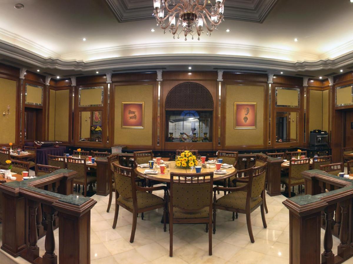 a dining room with tables and chairs and a chandelier at The Lalit Laxmi Vilas Palace in Udaipur