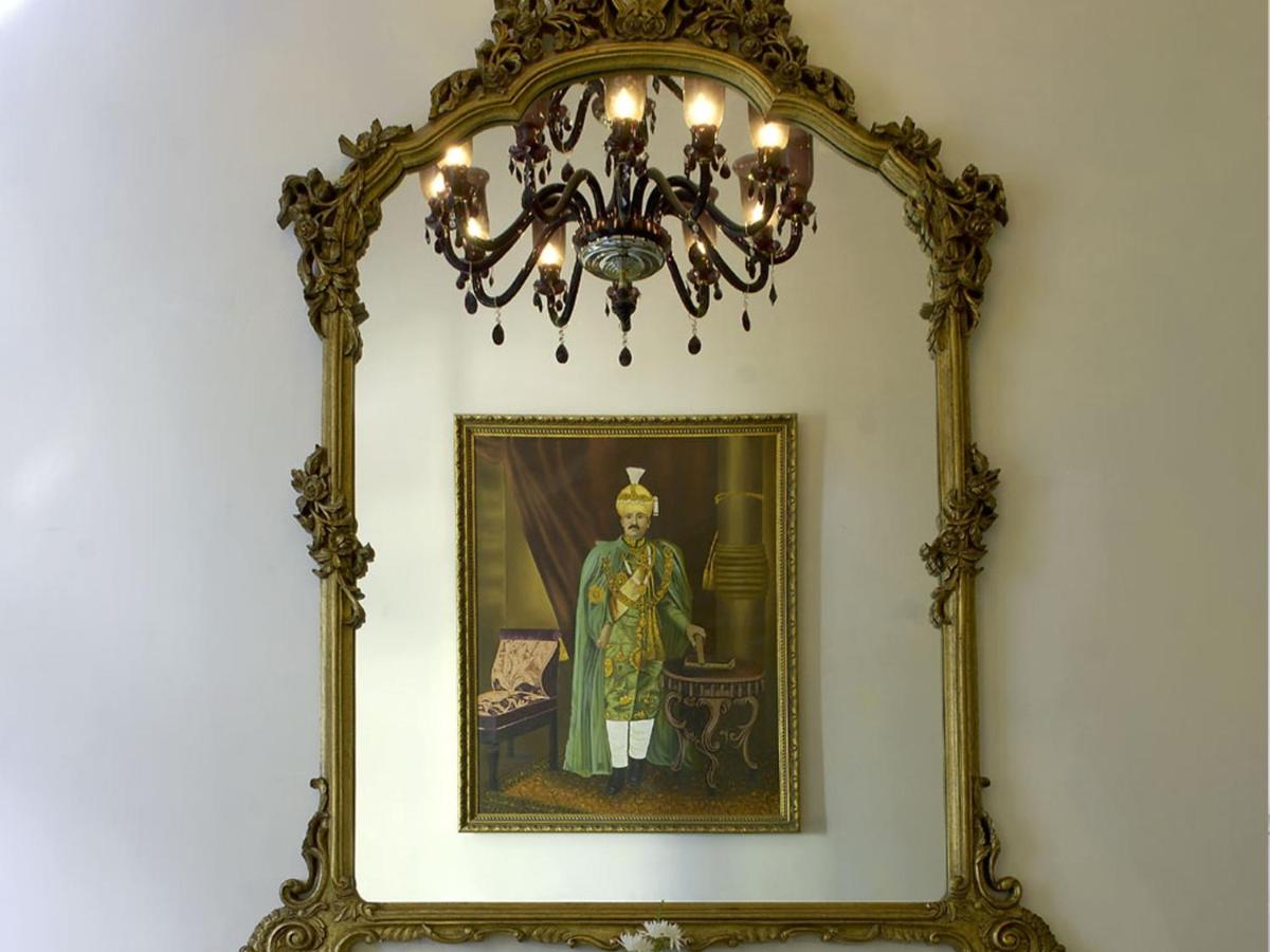 a mirror with a picture of a man on a wall at The Lalit Laxmi Vilas Palace in Udaipur