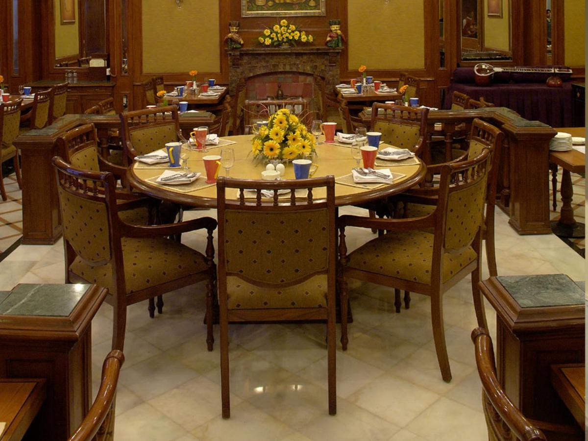 a dining room with a table with flowers on it at The Lalit Laxmi Vilas Palace in Udaipur