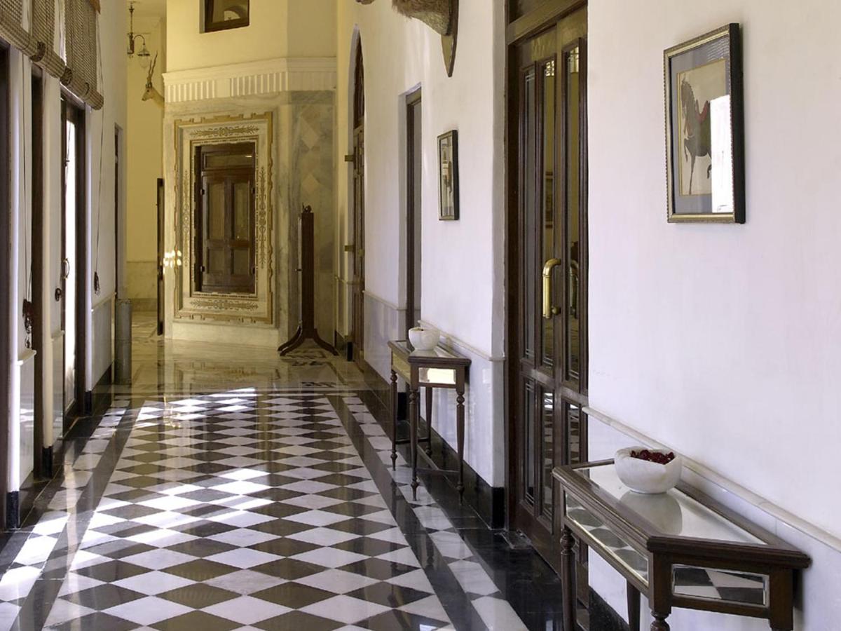 a hallway with a black and white checkered floor at The Lalit Laxmi Vilas Palace in Udaipur