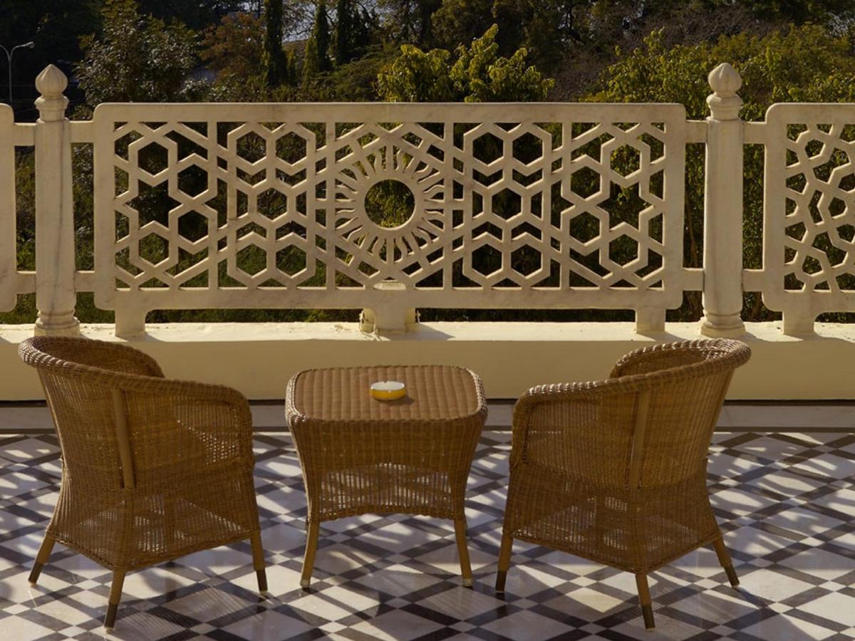 three chairs and a table in front of a fence at The Lalit Laxmi Vilas Palace in Udaipur