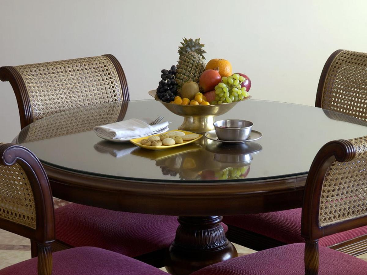 a glass table with a bowl of fruit on it at The Lalit Laxmi Vilas Palace in Udaipur