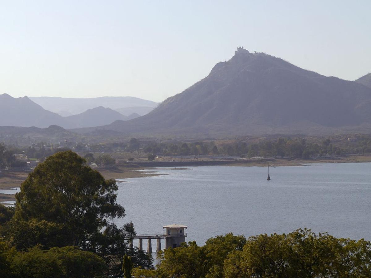 a large body of water with a mountain in the background at The Lalit Laxmi Vilas Palace in Udaipur