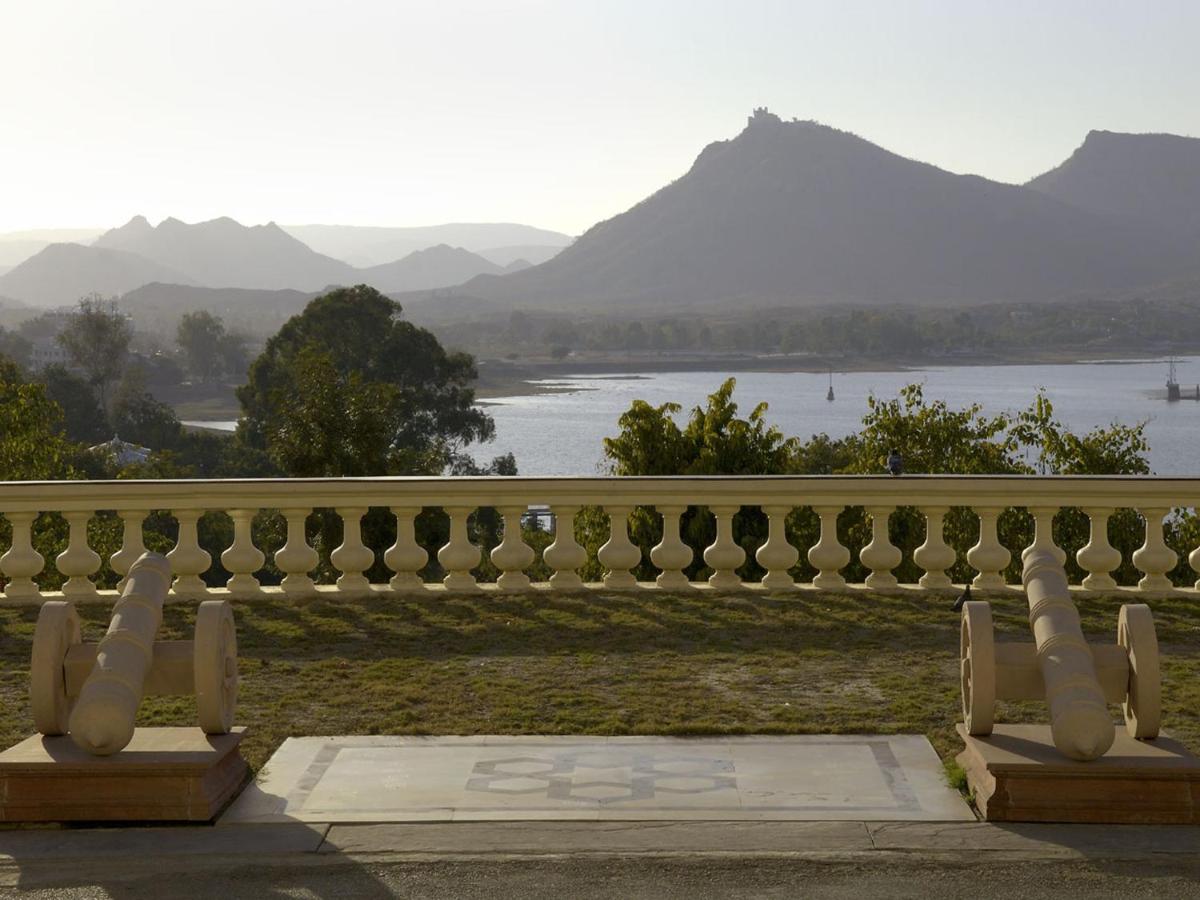 a white fence with a view of a river and mountains at The Lalit Laxmi Vilas Palace in Udaipur