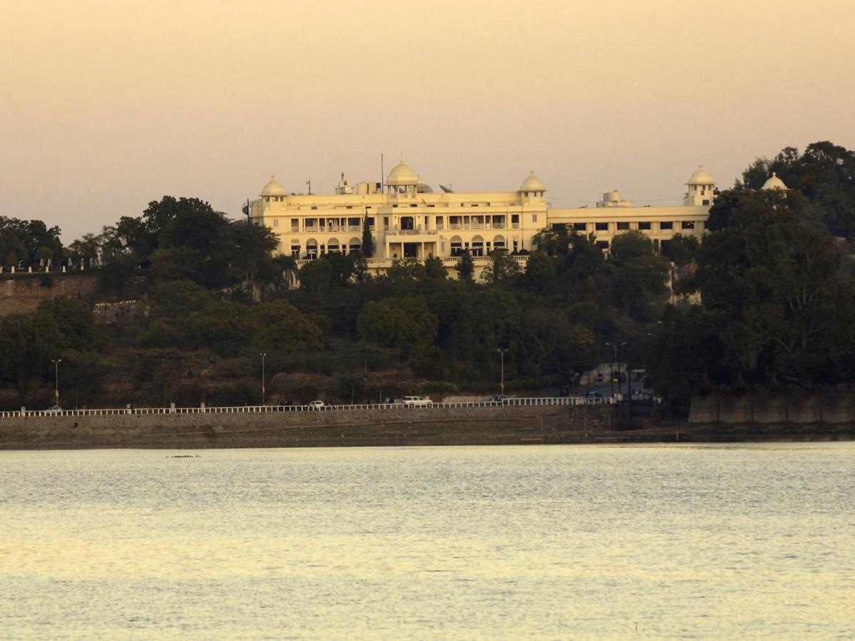 a large white building on a hill next to the water at The Lalit Laxmi Vilas Palace in Udaipur