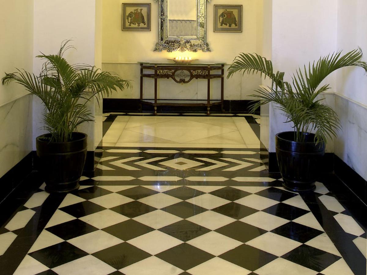a lobby with a checkered floor and two potted plants at The Lalit Laxmi Vilas Palace in Udaipur