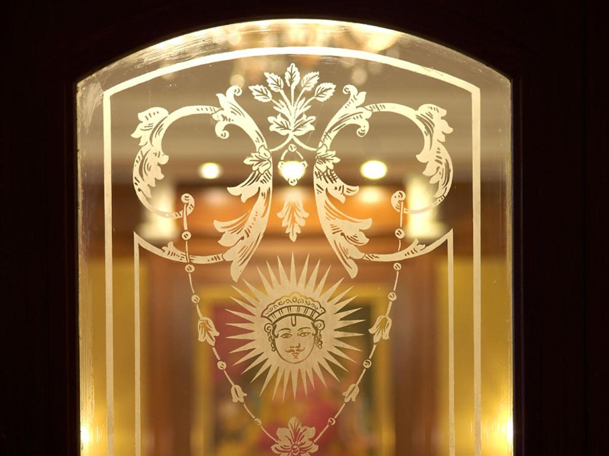 a gold frame with a picture of the sun and a mask at The Lalit Laxmi Vilas Palace in Udaipur