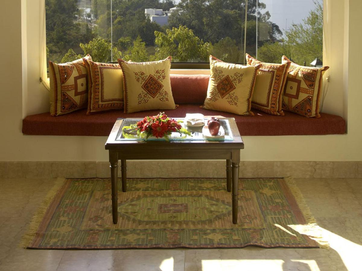 a coffee table in front of a couch with a window at The Lalit Laxmi Vilas Palace in Udaipur