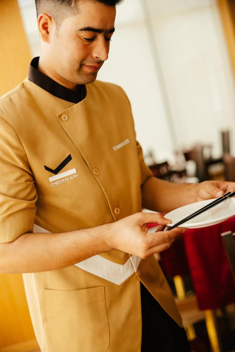 a man in a chef uniform holding a book at Sunday Hotel Chandigarh Zirakpur in Zirakpur
