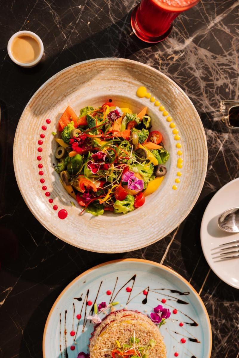 a table with a bowl of salad and a plate of food at Sunday Hotel Chandigarh Zirakpur in Zirakpur