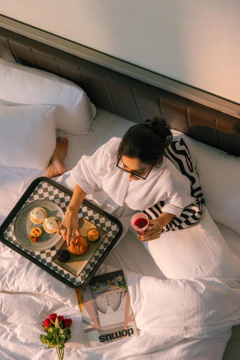 a woman laying on a bed with a tray of donuts at Sunday Hotel Chandigarh Zirakpur in Zirakpur