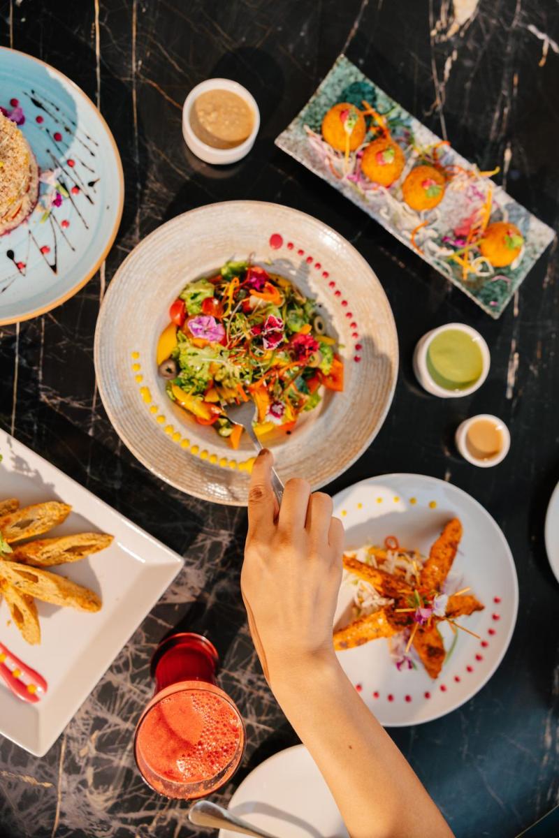 a person eating food on a table with plates of food at Sunday Hotel Chandigarh Zirakpur in Zirakpur