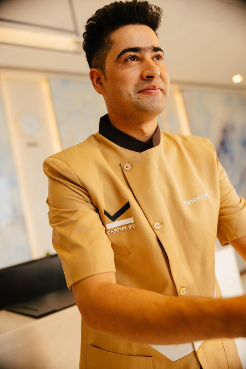 a man standing in a kitchen with his arms crossed at Sunday Hotel Chandigarh Zirakpur in Zirakpur