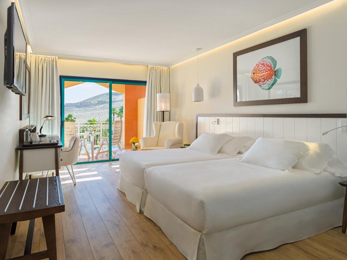 Una habitación de hotel con dos camas y balcón. en H10 Playa Esmeralda - Adults Only, en Costa Calma