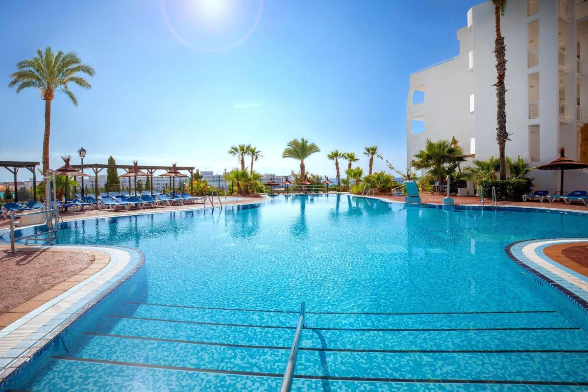 Una gran piscina con palmeras y un edificio. en Hotel Servigroup Marina Mar, en Mojácar