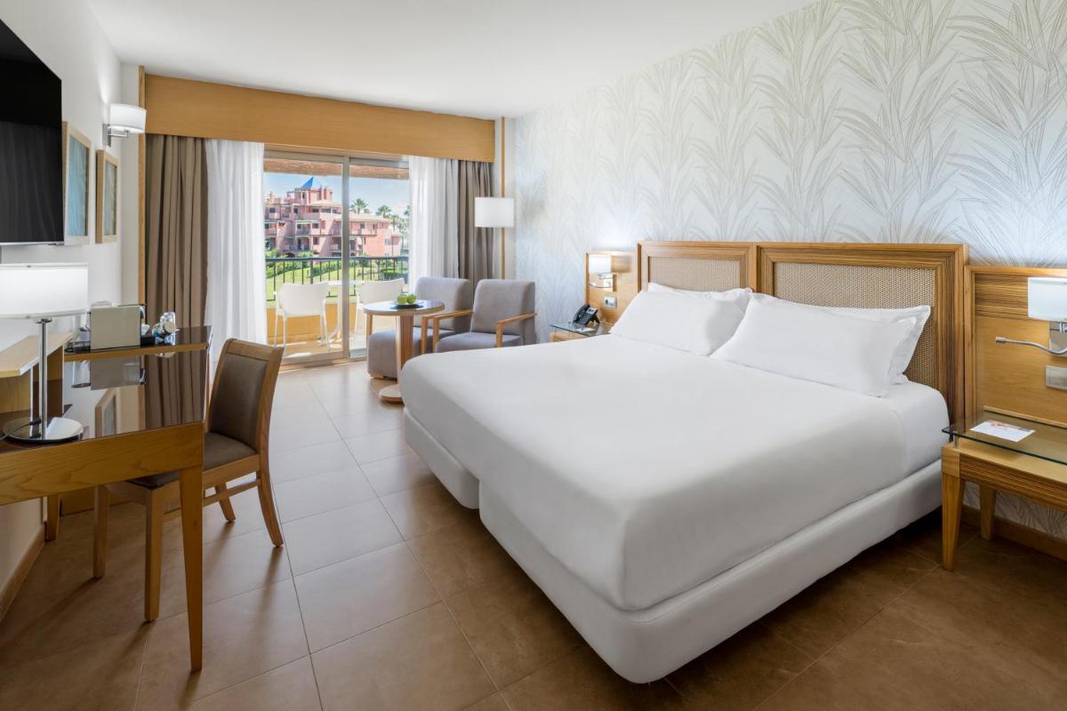 Una habitación de hotel con una gran cama blanca y un escritorio. en Elba Costa Ballena Beach & Thalasso Resort, en Costa Ballena