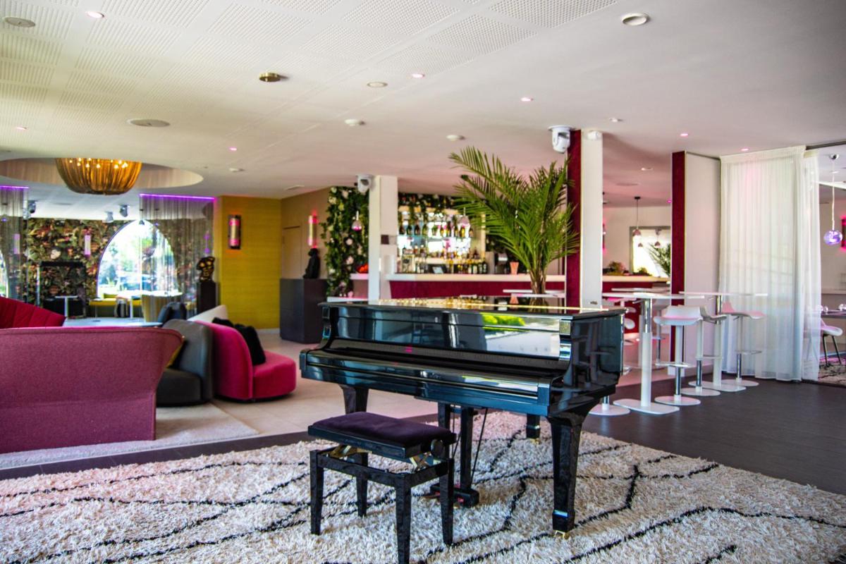 un piano noir dans un hall avec un bar dans l'établissement Oz'Inn Hôtel & Spa, au Cap d'Agde 36 autres photos