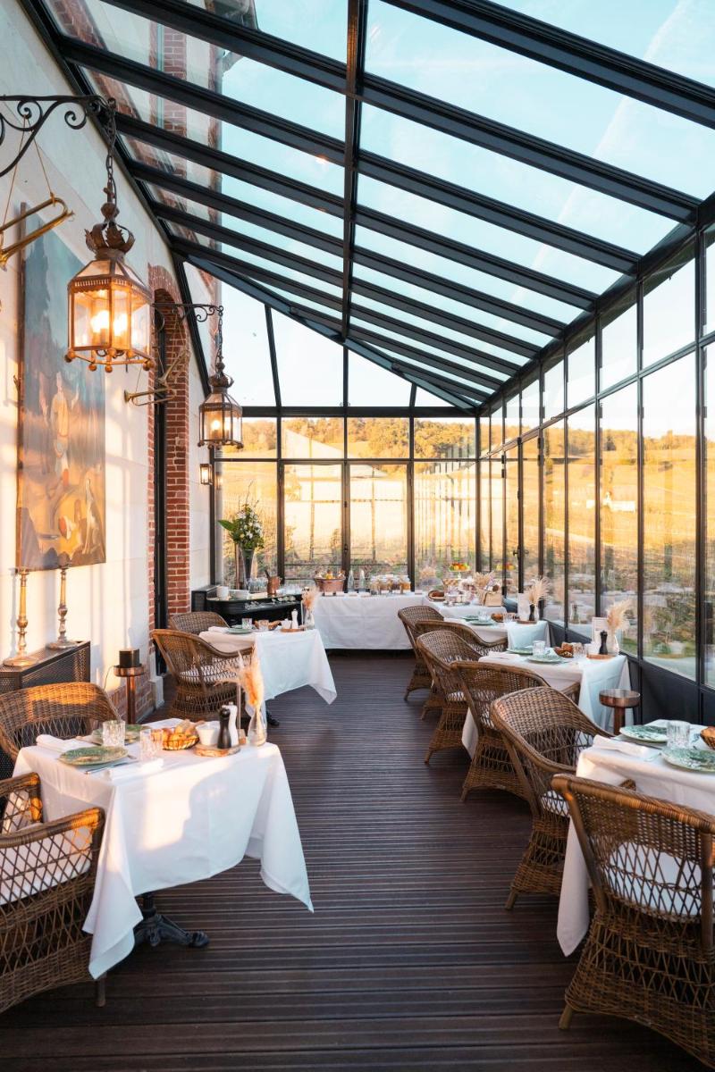 un restaurant avec des tables et des chaises blanches et des fenêtres dans l'établissement Chateau de Sacy, à Sacy