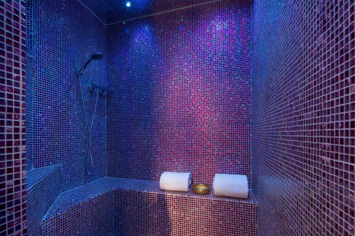une salle de bain avec des carreaux violets et une baignoire avec deux serviettes dans l'établissement Hotel & Spa de Latour Maubourg, à Paris 86 autres photos