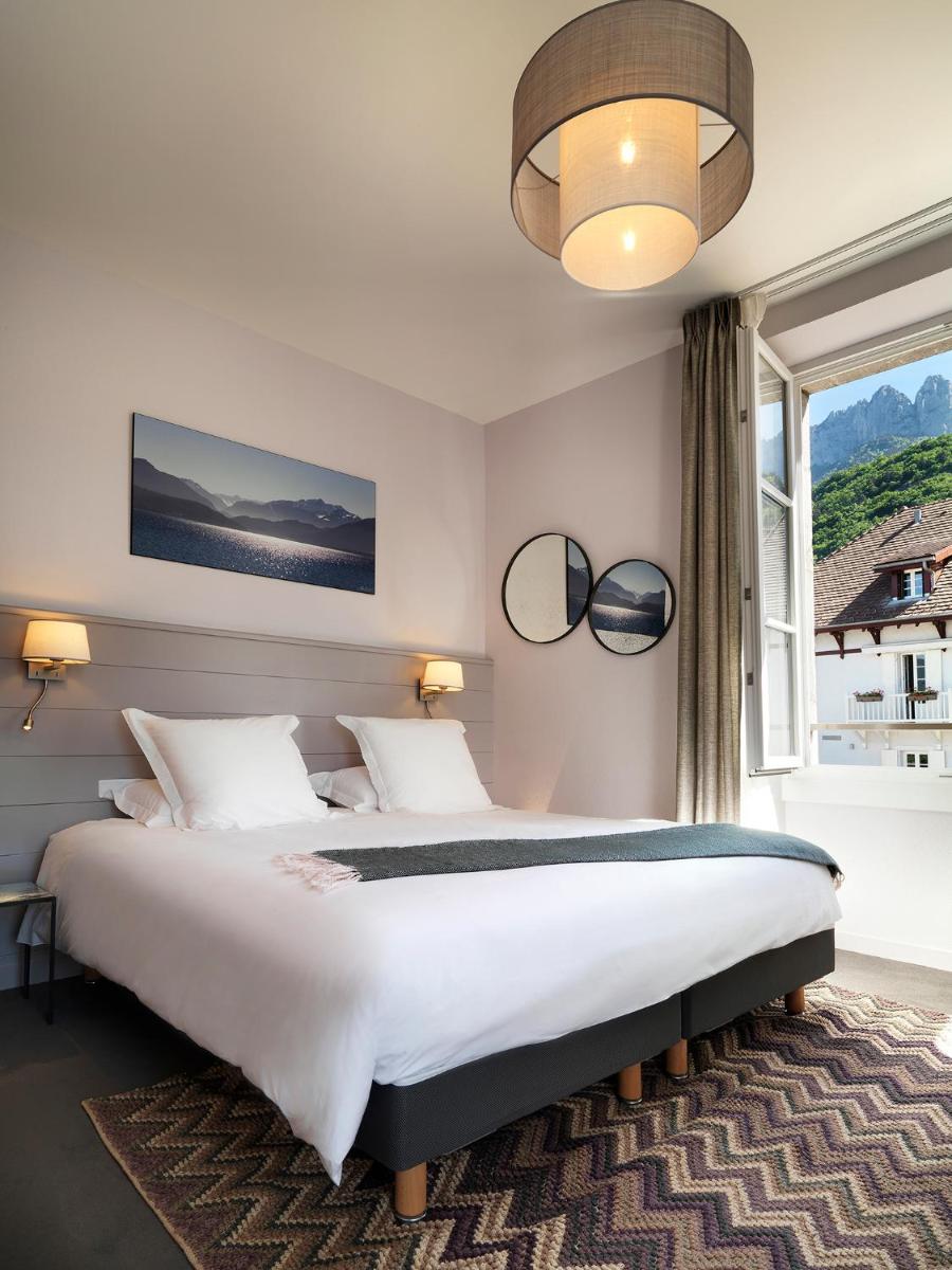une chambre avec un grand lit et une fenêtre dans l'établissement Hôtel Beau Site Talloires B SPA, à Talloires