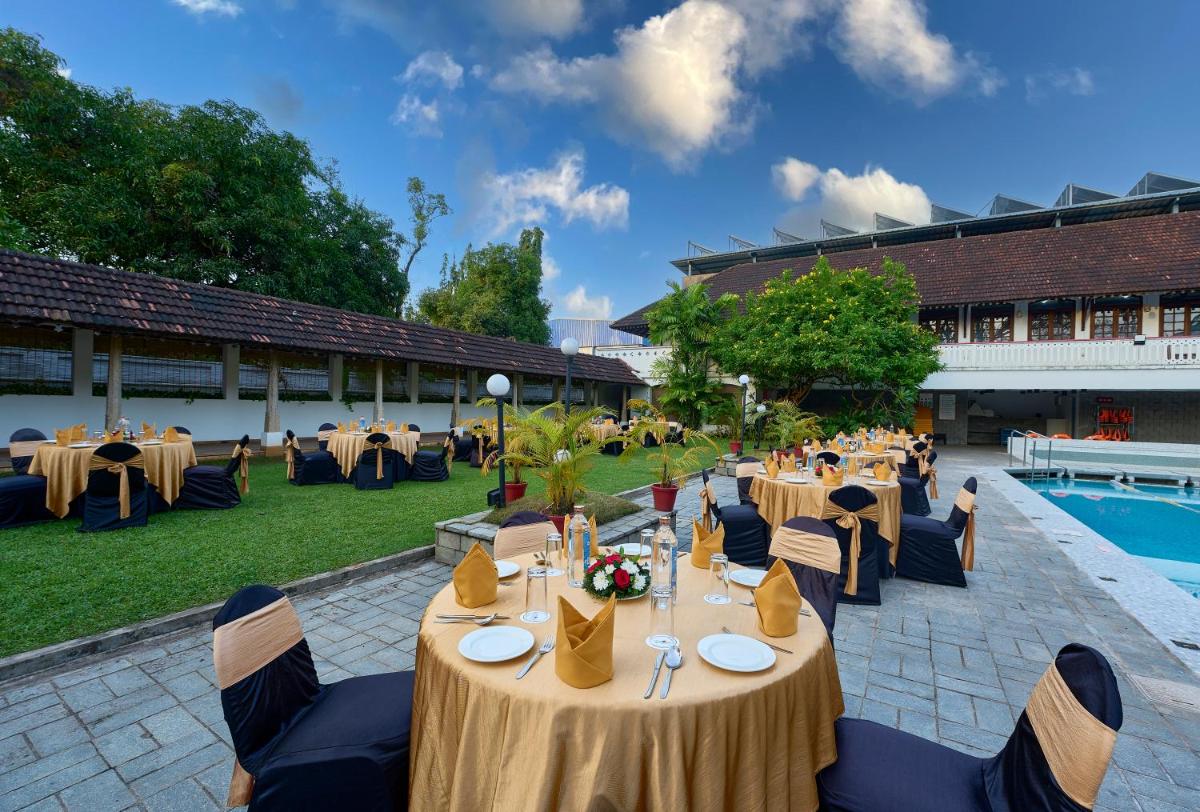 a restaurant with tables and chairs and a pool at Casino Hotel - CGH Earth, Cochin in Cochin