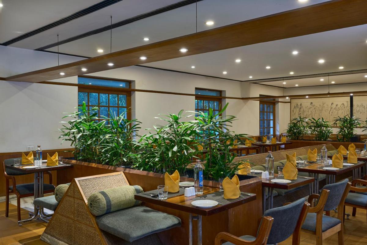 a restaurant with tables and chairs and plants at Casino Hotel - CGH Earth, Cochin in Cochin
